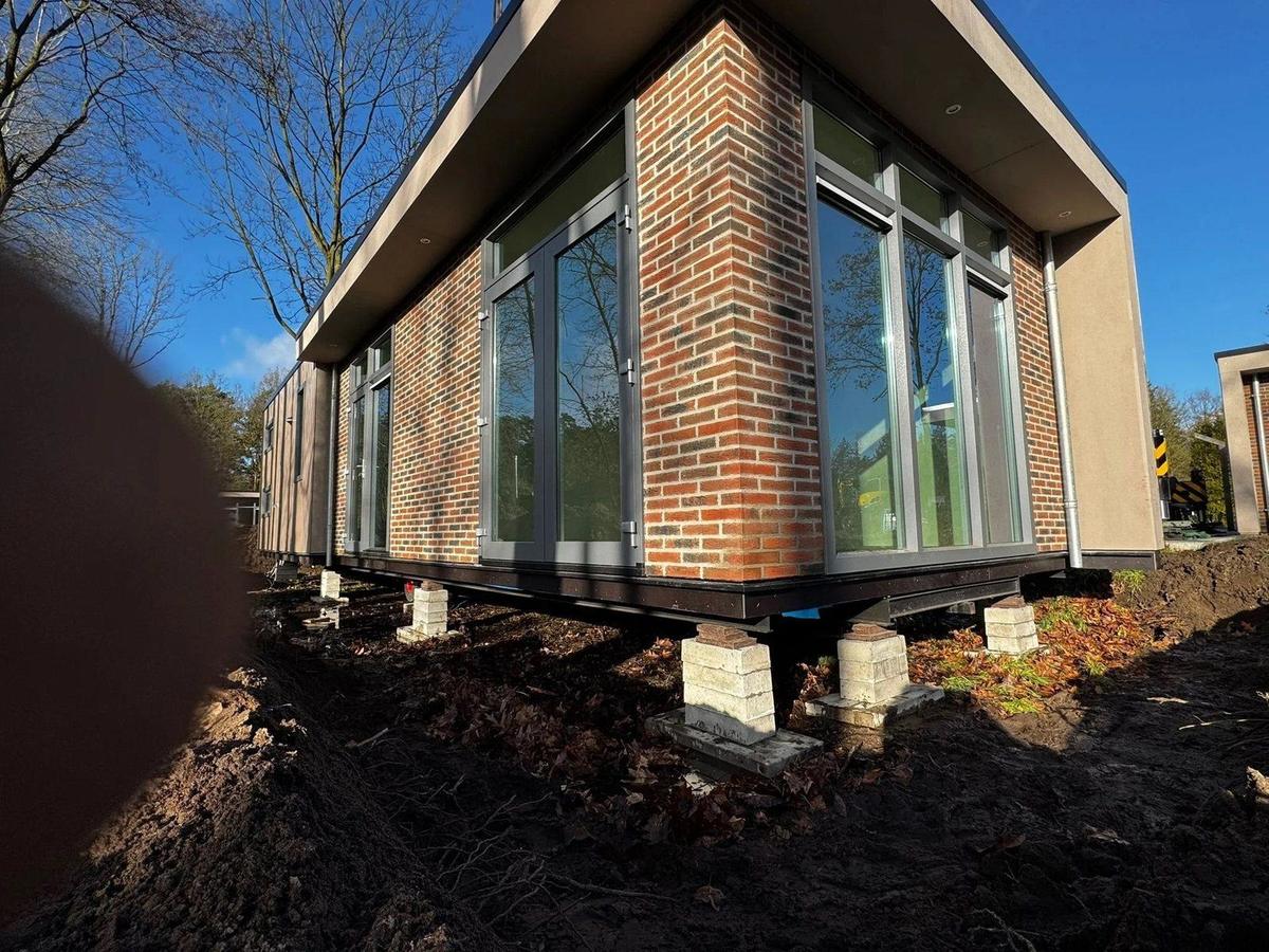 Een woning met bakstenen gevel staat op de stapels bielzen