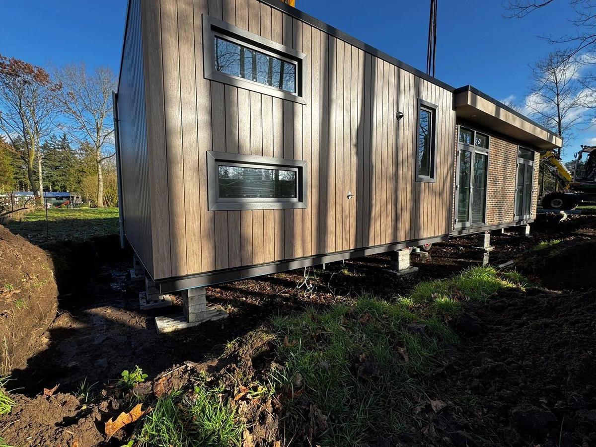 Een lang chalet met houten bekleding op stapels bielzen